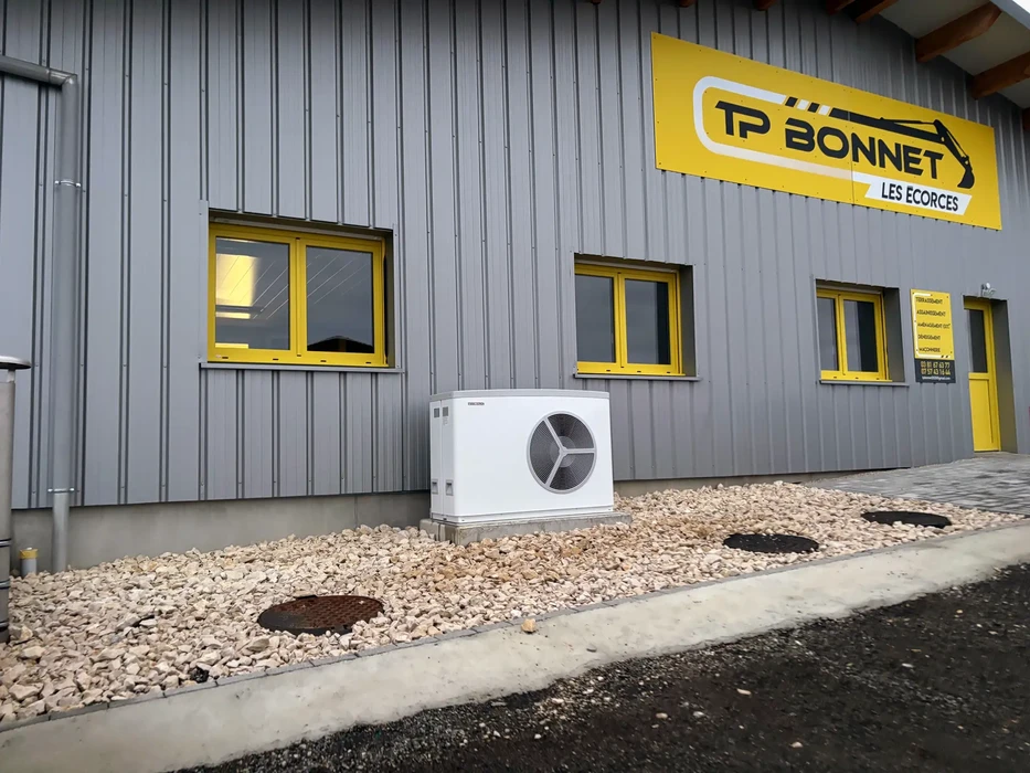 Façade extérieure d'un bâtiment industriel TP BONNET LES ECORCES avec bardage métallique gris et menuiseries jaunes