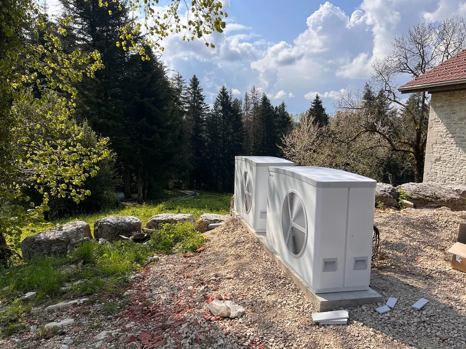 Scène extérieure d'installation de pompes à chaleur air-air dans jardin résidentiel avec pierres naturelles et végétation
