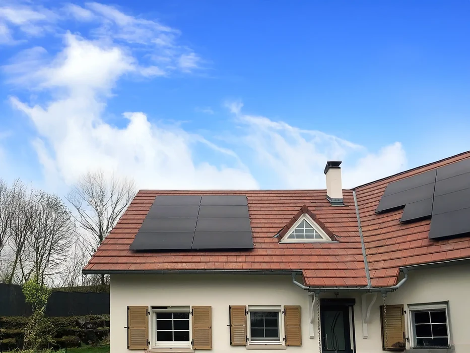 Deux techniciens installent des panneaux solaires photovoltaïques sur toiture résidentielle à tuiles rouges